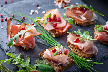 Sliced prosciutto with herbs and pomegranate seeds
