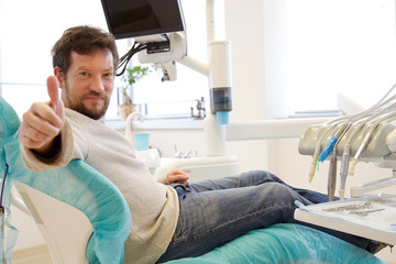 Happy man in dentist studio after operation