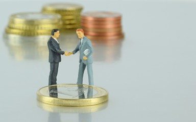 Miniature businessmen sealing a financial deal with a handshake