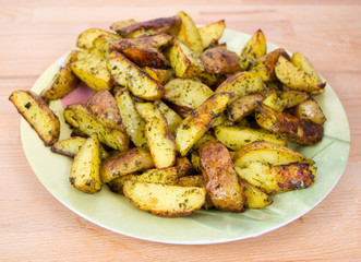 young baked potatoes with spices on a wooden hardboard