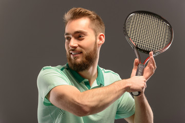 Handsome young man in polo shirt holding tennis racket