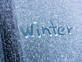 Word -winter- written by finger on snowy car windshield