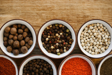 Various peppers in ceramic dishes on the wooden table
