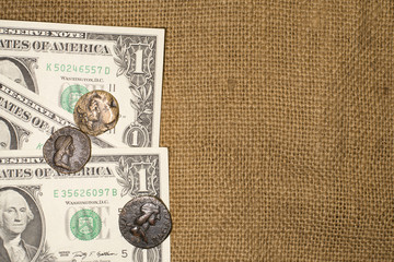 Ancient coins and dollar notes on sacking