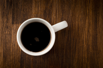 White cup of coffee on vintage wood.