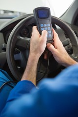 Naklejka premium Mechanik za pomocą narzędzia diagnostycznego w samochodzie