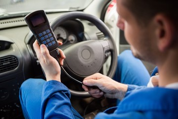 Naklejka premium Mechanic using diagnostic tool in the car