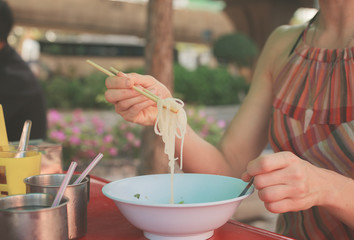 Obraz na płótnie Canvas Woman eating noodles in the street