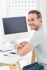 Smiling businessman sitting at desk typing on keyboard
