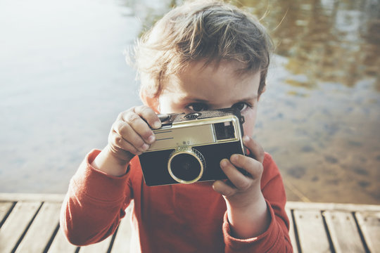 Portrait of a smiling cute boy taking picture with retro camera