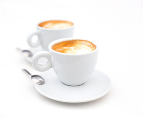 Two white cups of Cappuccino coffee with heart shaped milk foam
