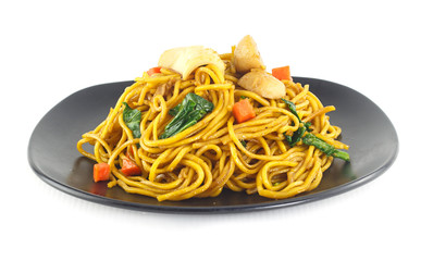 Dish of stir fried yellow noodles with meat and vegetable on whi