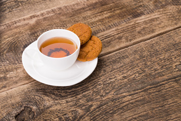ivory tea cup with sweet cookie on wooden palette
