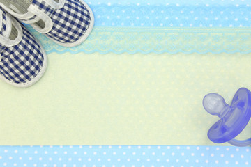 Baby shoes and blue pacifier on polka dots background 