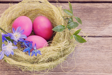 Easter egg nest with flowers on rustic wooden background
