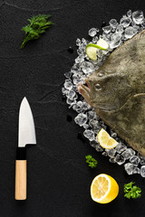 Fresh turbot fish on ice on a black stone table top view