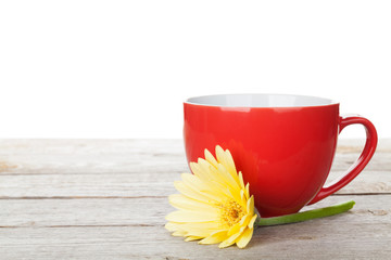 Cup of coffee and gerbera on wooden table