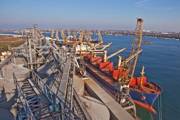 Grain from silos being loaded onto cargo ship on conveyor belt © sarymsakov.com