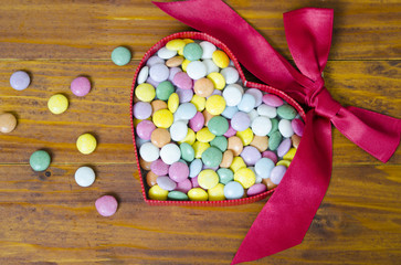 Colorful chocolate pills in a heart shaped box