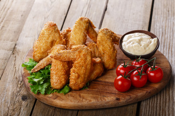 Fried chicken wings with sauce and tomatoes