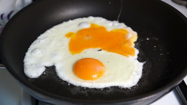 Two fried egg yolks fried in a stone pan on a gas stove