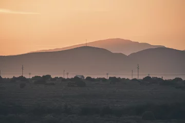 Foto op Plexiglas Truck driving through mountain semi desert landscape at sunrise. © ysbrandcosijn