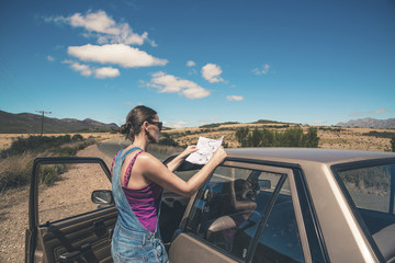 Woman standing next to old car reading a map. Swartberg. Western