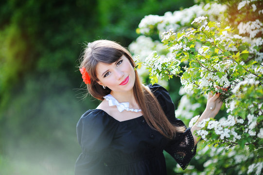 beautiful girl with a red bow in the spring flowery park