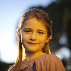 Niña rubia con vestido marrón al atardecer