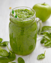 Apple and spinach smoothie in glass on a wooden background