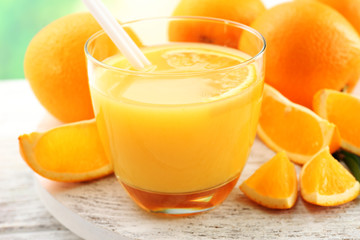 Fototapeta na wymiar Glass of orange juice with straw and slices