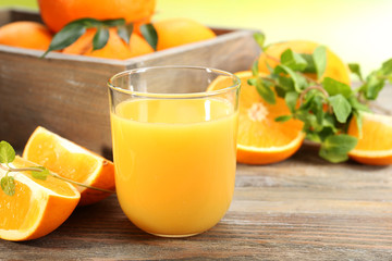 Glass of orange juice with crate of oranges and slices