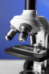 Microscope on table, on color background, close-up