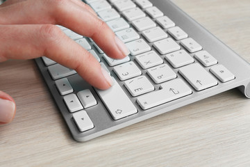 Female hand with keyboard on wooden desktop background