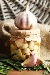 Canned garlic in glass jar and wicker mat and rosemary