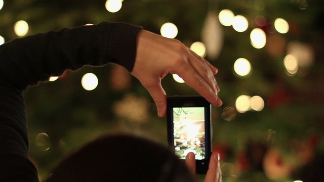 Hands taking picture of christmas tree, close up