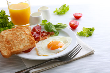Bacon and eggs on color wooden table and white background