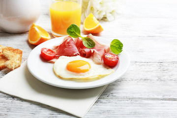 Bacon and eggs on color wooden table background.