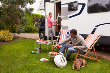 Couple In Van Enjoying Barbeque On Camping Holiday