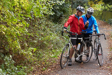 Two Mature Male Cyclists On Ride Looking At Mobile Phone App