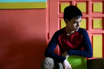 Young Teen Sitting on a Chair Against a colorful wall