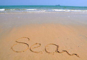 The word Sea is written on a sand background