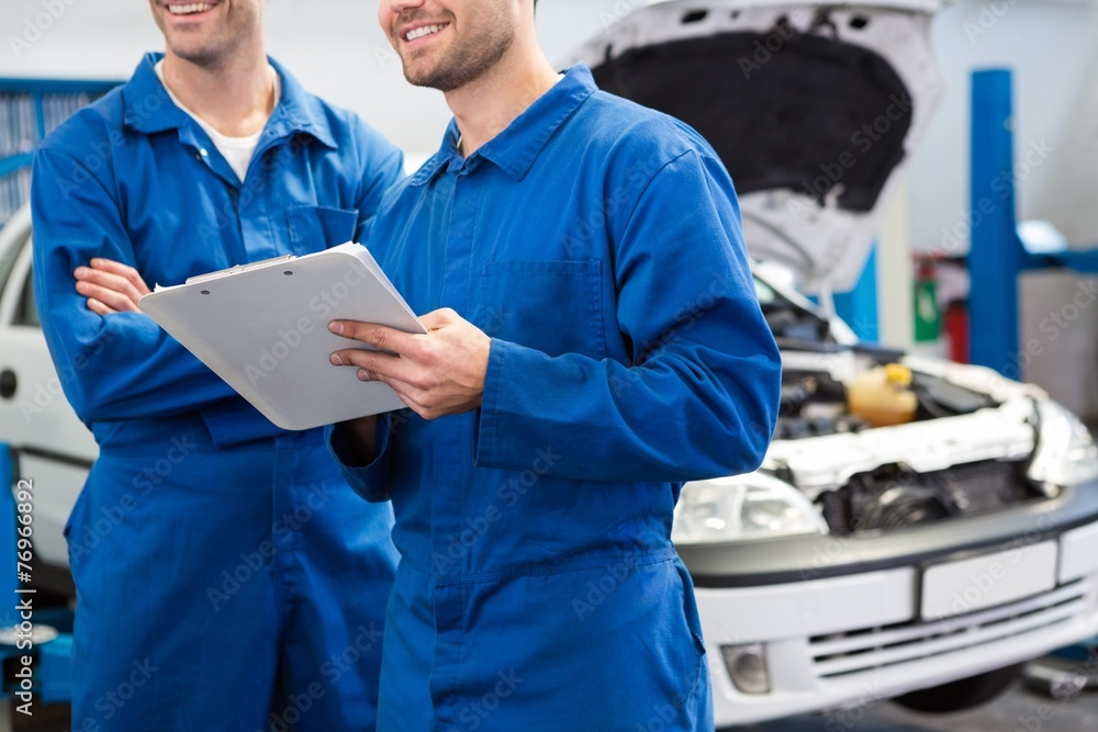 Poster smiling mechanic working together on clipboard
