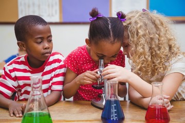 Cute pupil looking through microscope