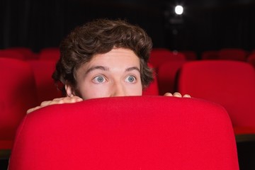 Young man watching a scary film