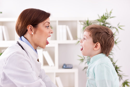 Child patient with doctor showing .tongue, examination.throat