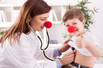 Smiling doctor examining success child with finger up