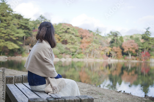 秋の紅葉の公園の池の前のベンチに座る女性 Wall Mural Milatas 秋の紅葉の公園の池の前のベンチに座る女性 Wall Mural Milatas