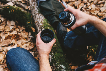 Traveler man pours tea from thermos outdoor