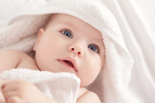 Baby with blus eyes under the white towel